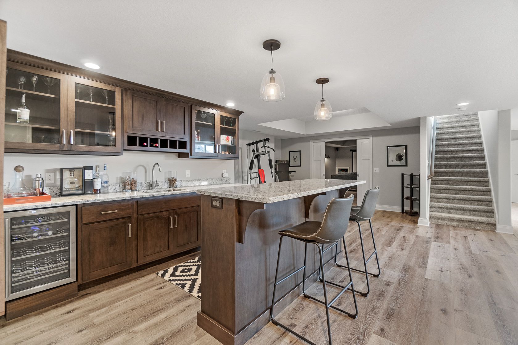Lower-level bar with dark cabinetry and wine fridge