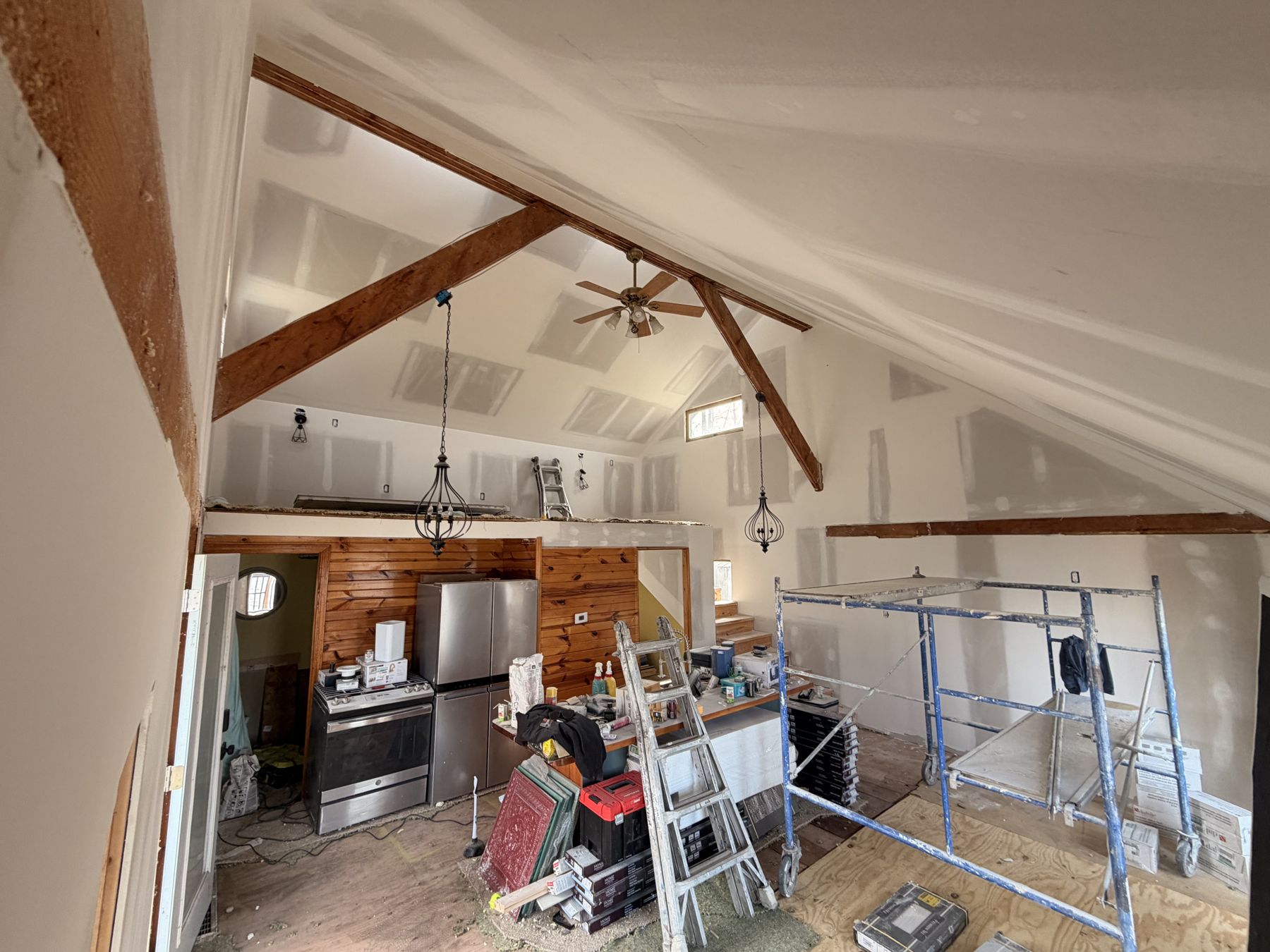The main room mid-renovation: bare drywall, scaffolding, exposed beams