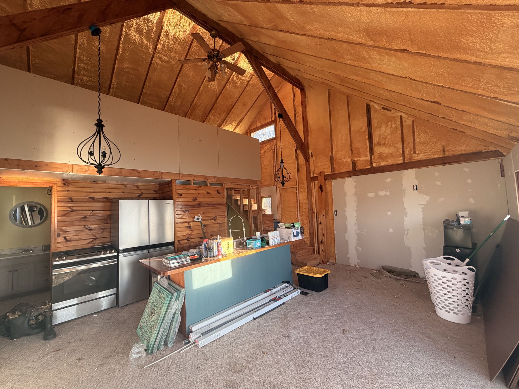 Kitchen before: wood panelling, exposed insulation, bare subfloor