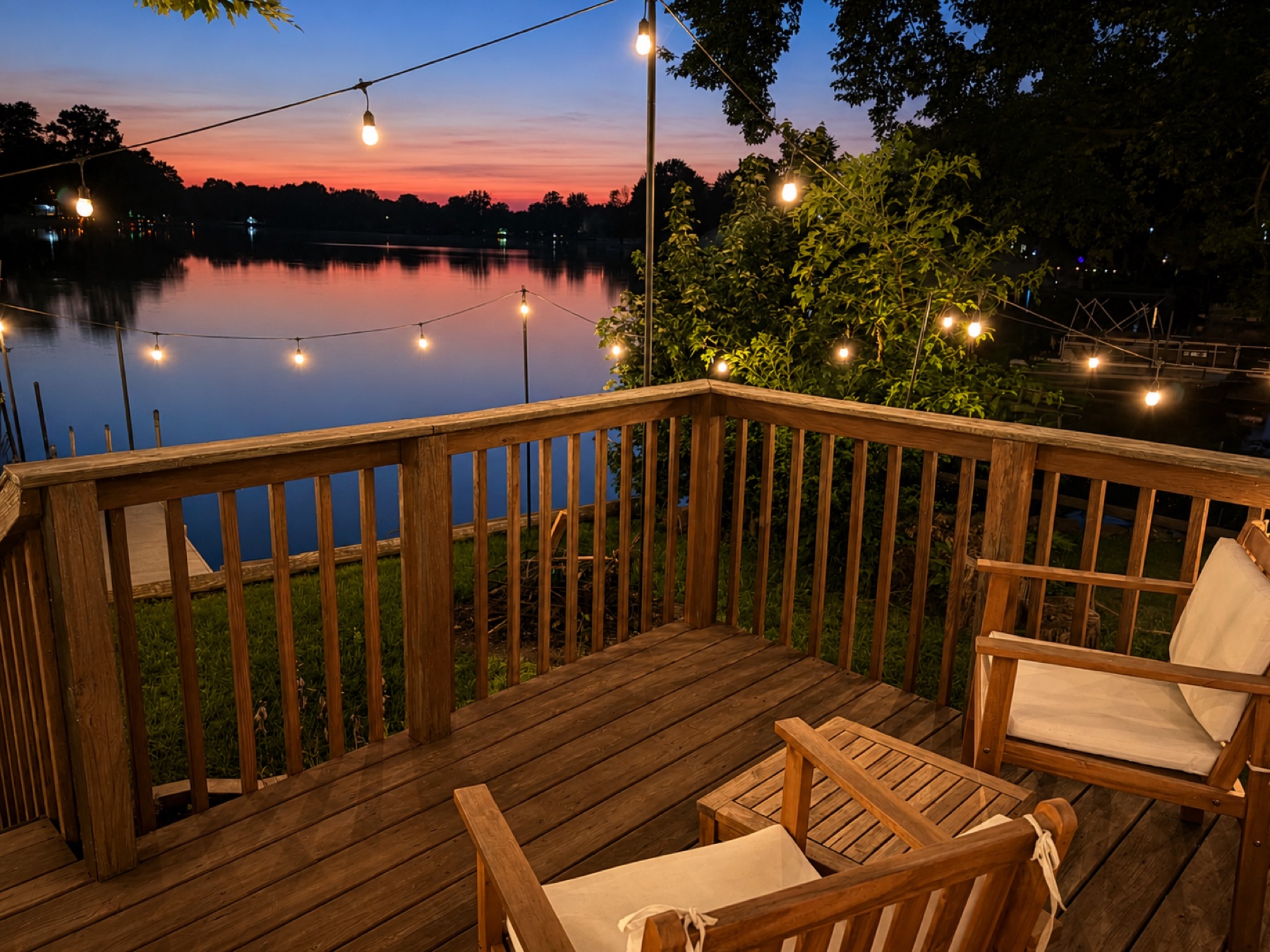 Two wooden deck chairs facing a pink and orange sunset over the lake