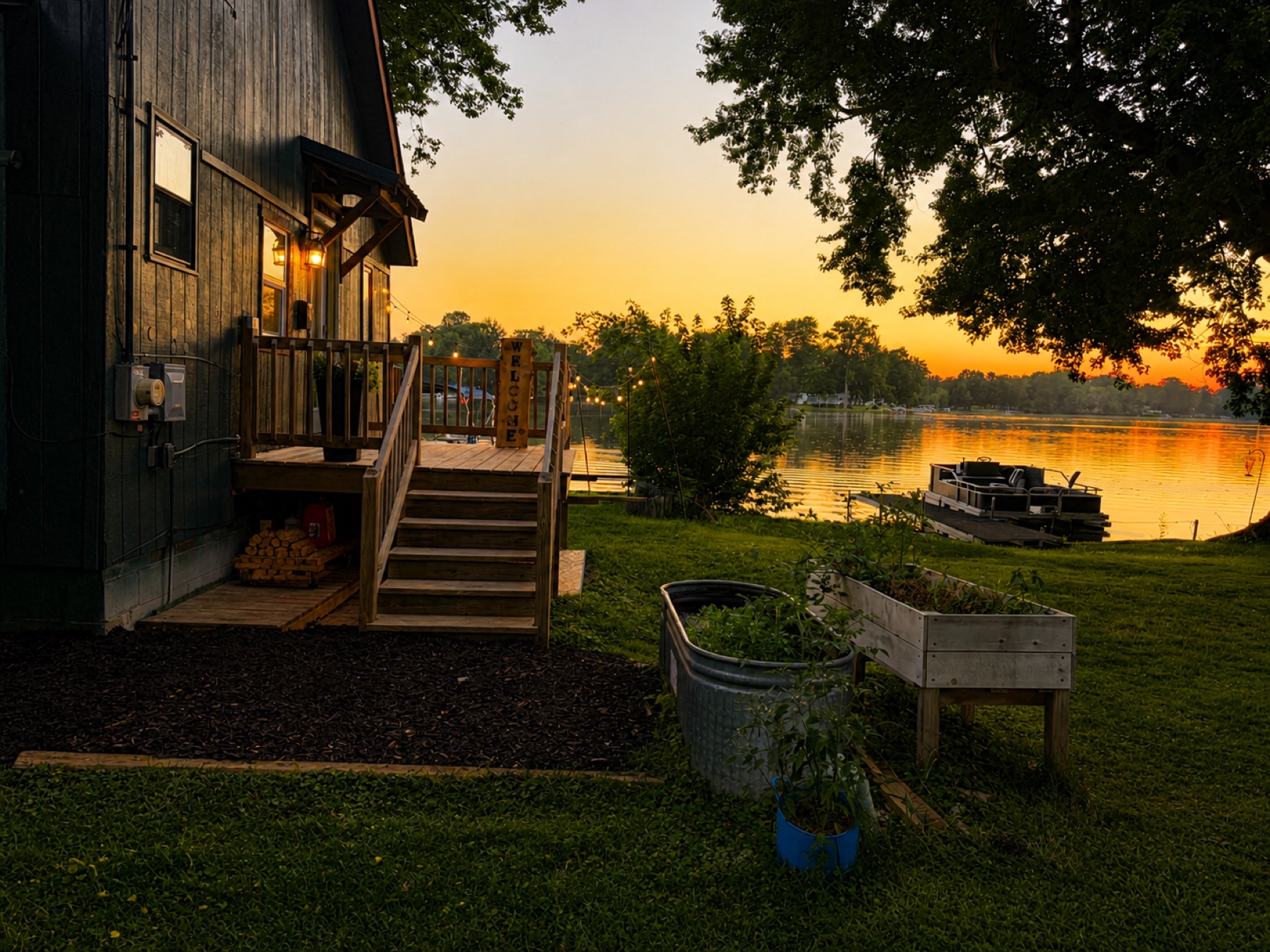 The cottage at golden hour with the lake glowing behind raised garden beds