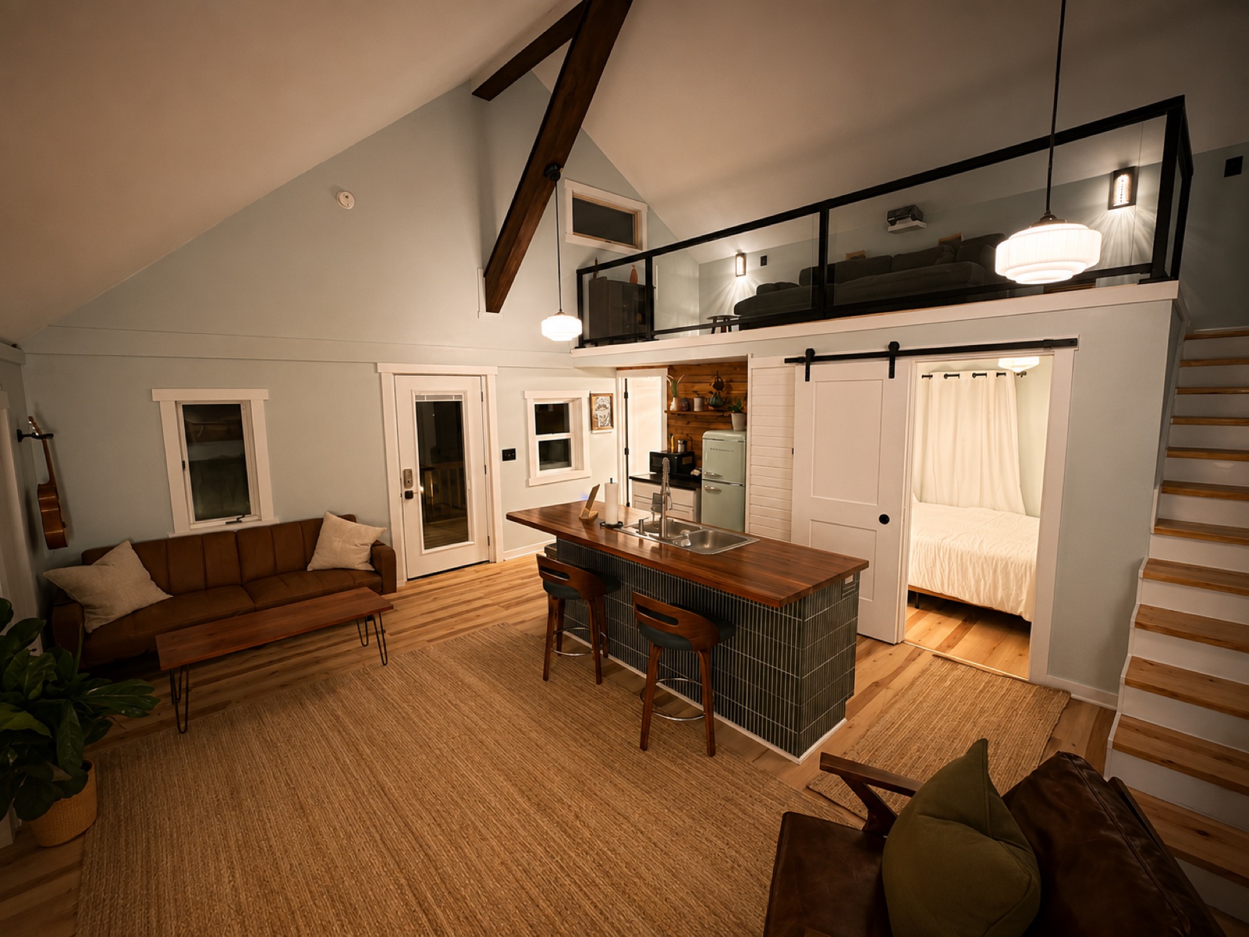 Living room with leather sofa, jute rug, and a barn door leading to the bedroom
