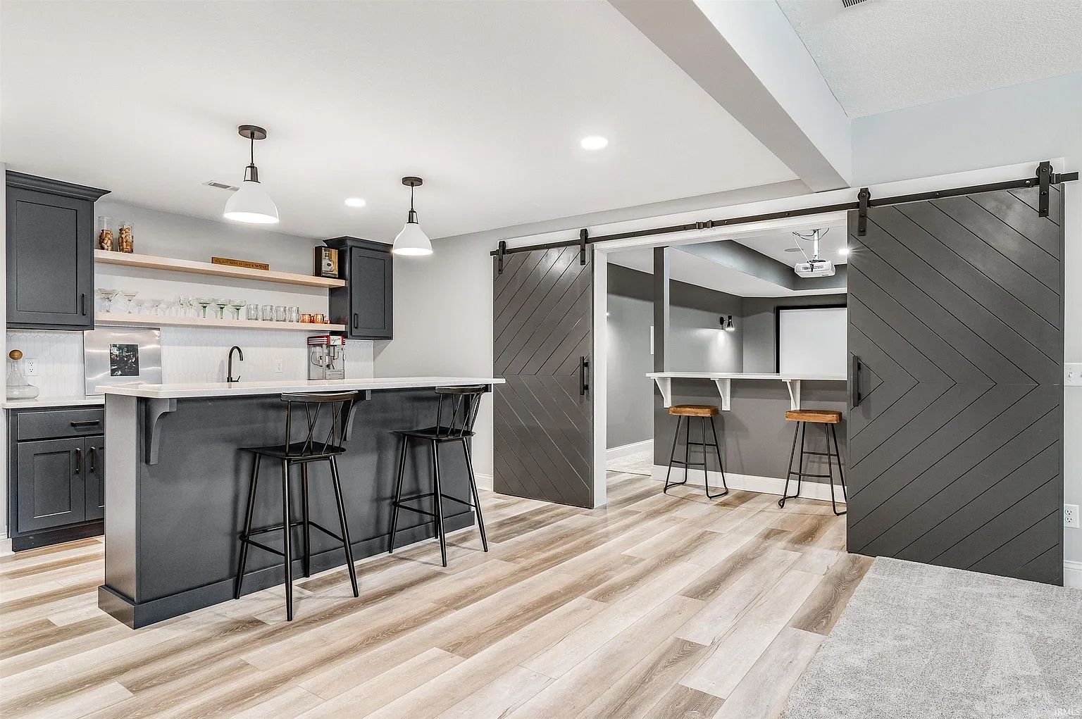 Kitchen with dark island, pendant lights and sliding barn door to the pantry