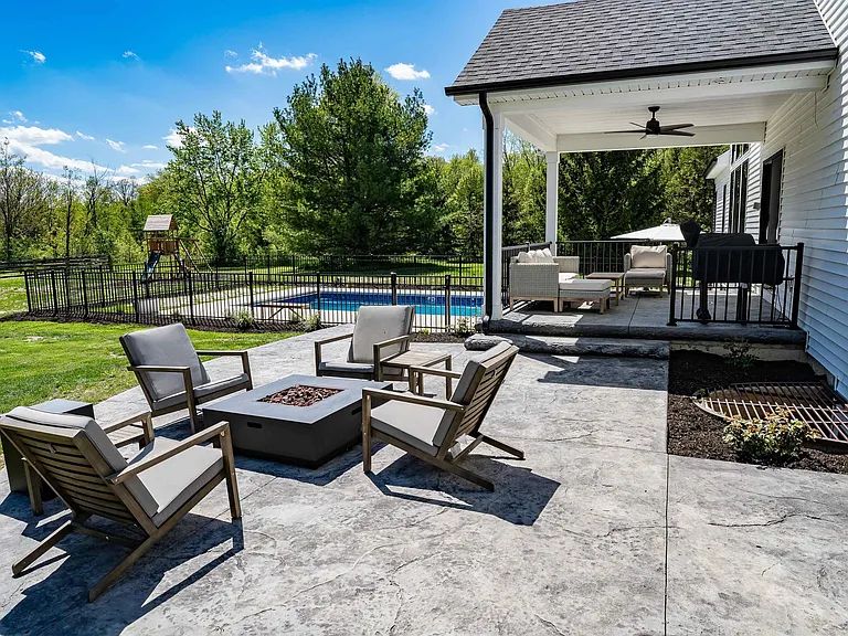 Back patio with fire table, covered porch and in-ground pool